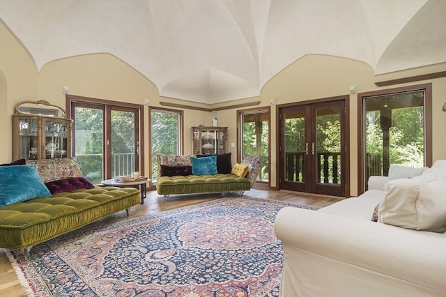 living room featuring hardwood / wood-style floors, brick ceiling, lofted ceiling, and french doors