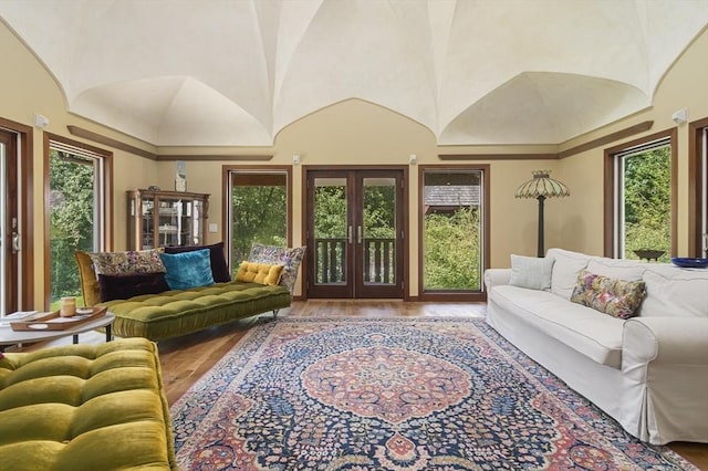 living room with wood-type flooring, lofted ceiling, and french doors