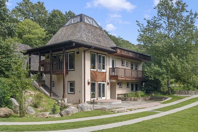 rear view of house featuring a balcony and a lawn