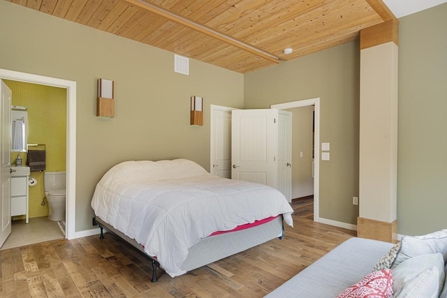 bedroom with light wood-type flooring, connected bathroom, and wood ceiling