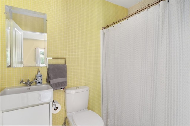 bathroom with toilet, vanity, and tasteful backsplash