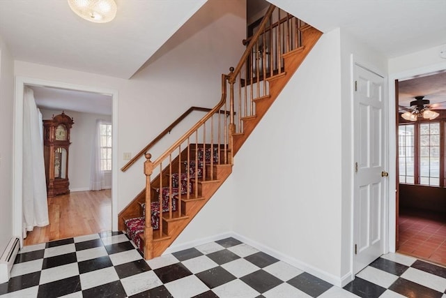 stairs featuring a baseboard radiator and ceiling fan