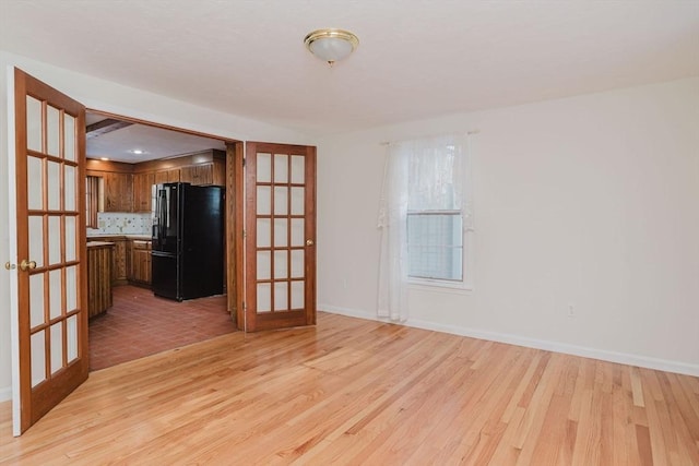 spare room featuring french doors and light wood-type flooring