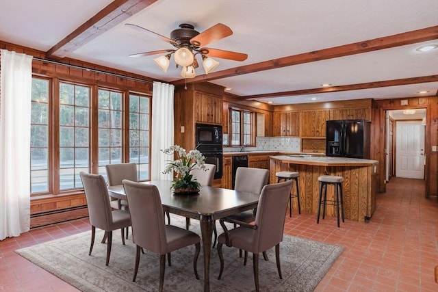 dining space with light tile patterned floors, beam ceiling, ceiling fan, and wood walls