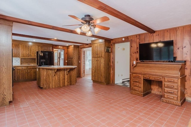 kitchen with beam ceiling, a kitchen breakfast bar, black refrigerator with ice dispenser, kitchen peninsula, and wood walls