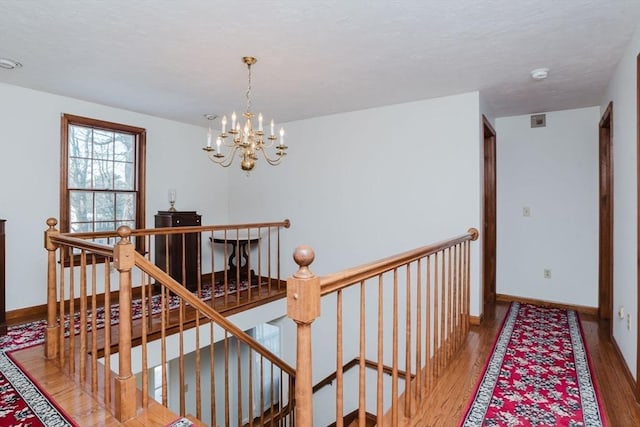 hallway with an inviting chandelier and wood-type flooring