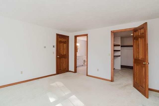 unfurnished bedroom with light carpet, a walk in closet, and a closet