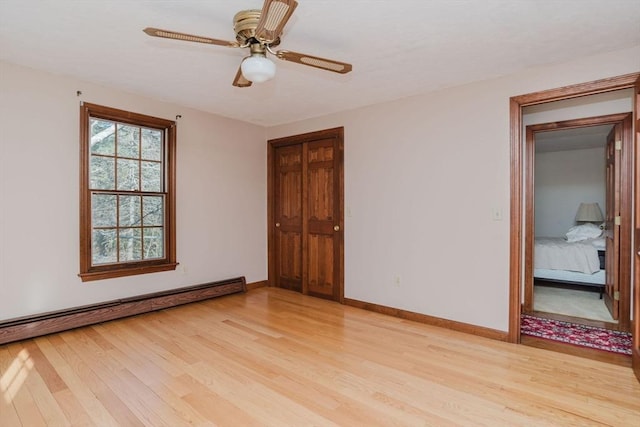 empty room with a baseboard heating unit, ceiling fan, and light hardwood / wood-style flooring