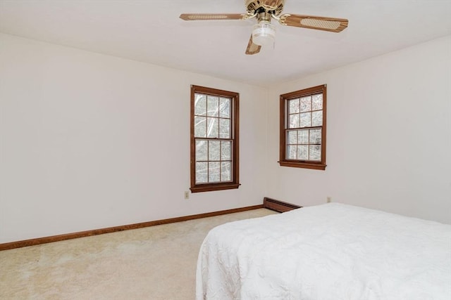 carpeted bedroom featuring a baseboard heating unit and ceiling fan