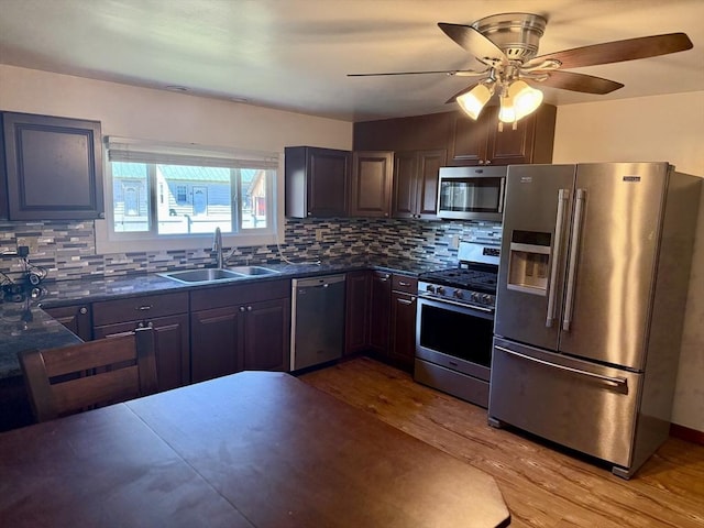 kitchen featuring a sink, light wood-style flooring, appliances with stainless steel finishes, and dark countertops
