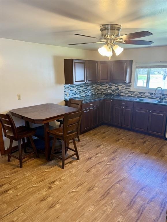 kitchen with a sink, dark countertops, tasteful backsplash, and light wood-style flooring