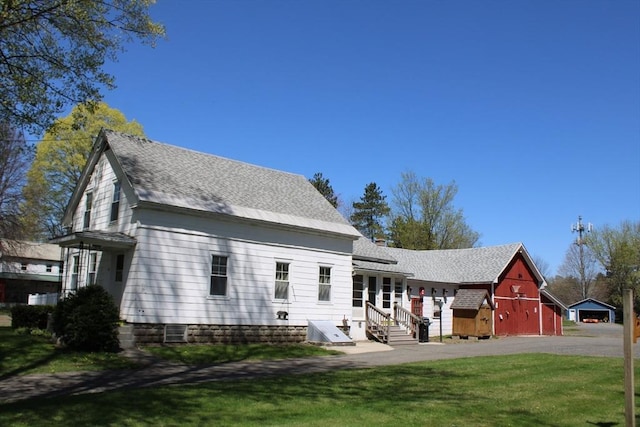 back of property featuring an outdoor structure, a barn, and a yard