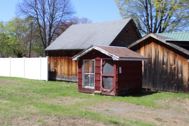 view of side of property featuring a yard, fence, and an outbuilding