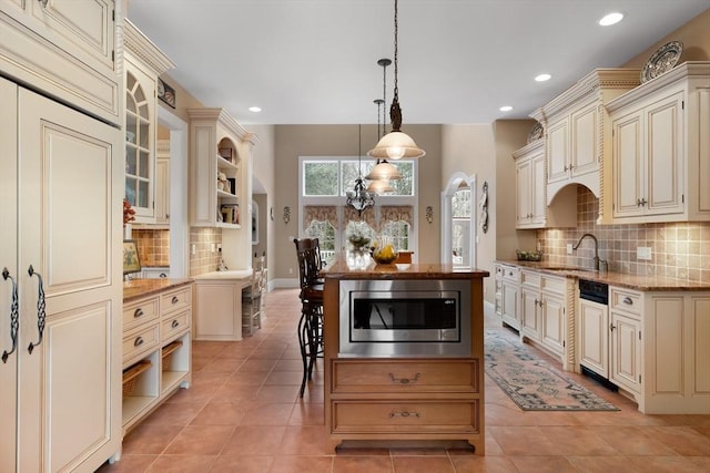 kitchen featuring cream cabinetry, pendant lighting, open shelves, and stainless steel microwave