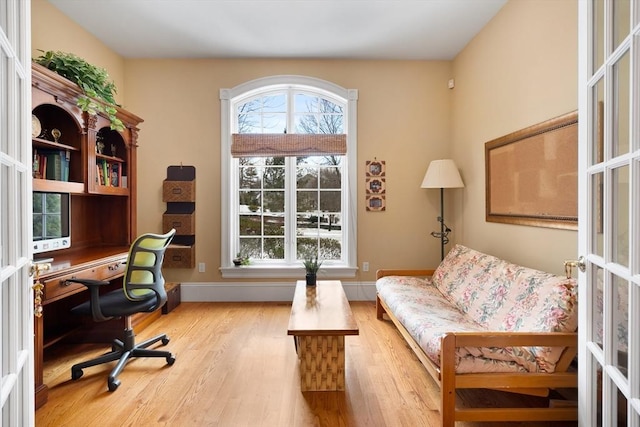 home office featuring french doors, light wood-style flooring, a wealth of natural light, and baseboards