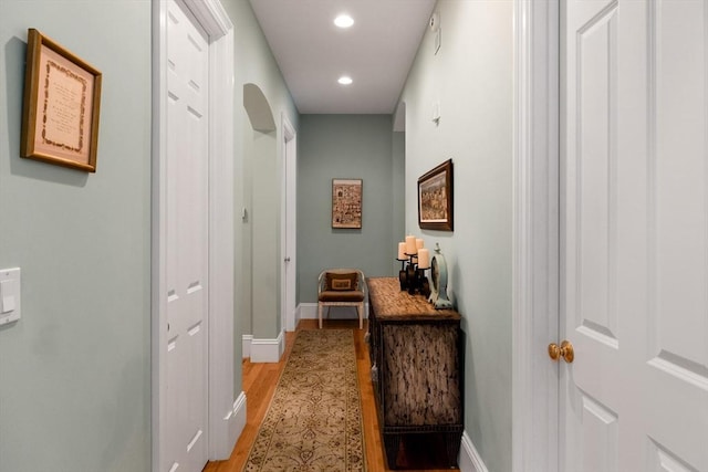 corridor featuring baseboards, light wood-type flooring, and recessed lighting