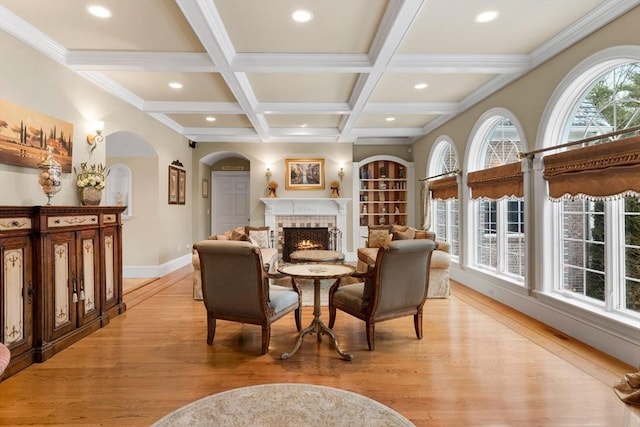 interior space with light wood-style flooring, recessed lighting, beam ceiling, and a lit fireplace