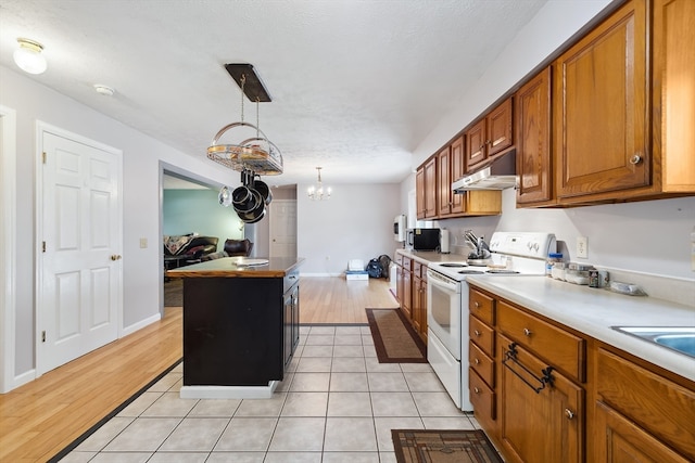 kitchen featuring a kitchen island, a notable chandelier, hanging light fixtures, white electric range oven, and light wood-type flooring