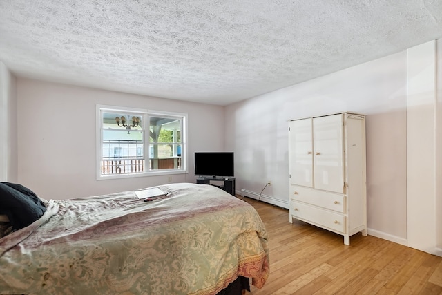 bedroom featuring a baseboard radiator, a textured ceiling, and light hardwood / wood-style flooring