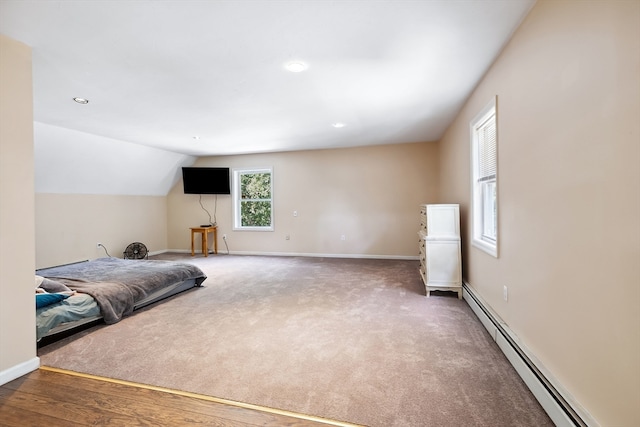 bedroom with vaulted ceiling, baseboard heating, and hardwood / wood-style floors