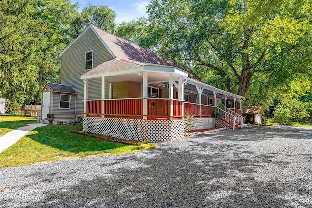 view of front of house with an outdoor structure, a front lawn, and a porch