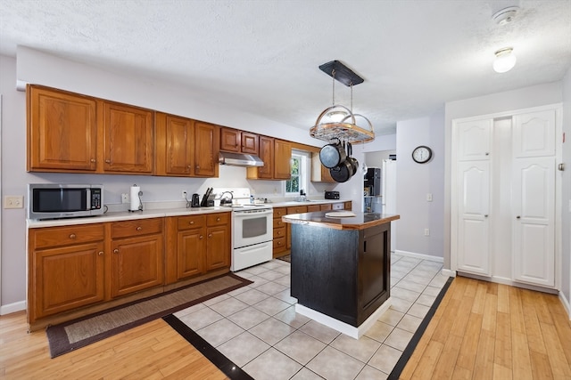 kitchen featuring pendant lighting, a textured ceiling, white electric stove, a kitchen island, and light hardwood / wood-style floors