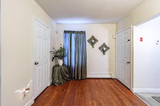 interior space with baseboard heating, dark wood-type flooring, and a textured ceiling