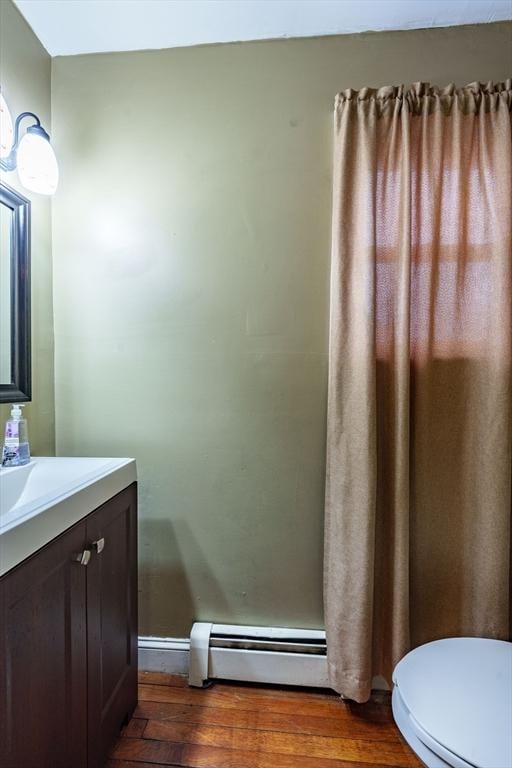 bathroom with hardwood / wood-style flooring, vanity, toilet, and a baseboard heating unit