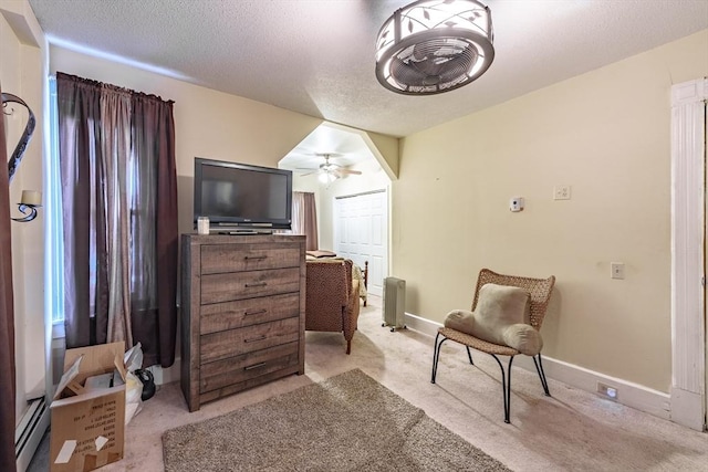 living area featuring ceiling fan, light carpet, and a textured ceiling