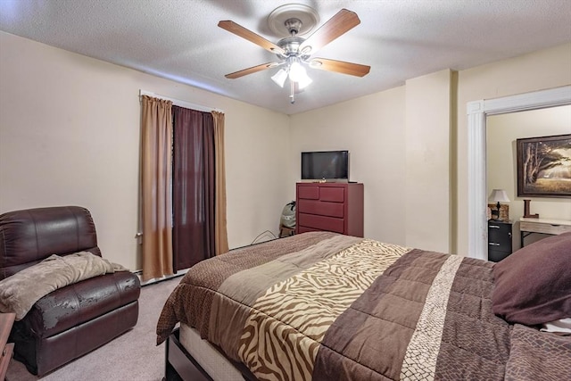 bedroom with ceiling fan, light colored carpet, and a textured ceiling