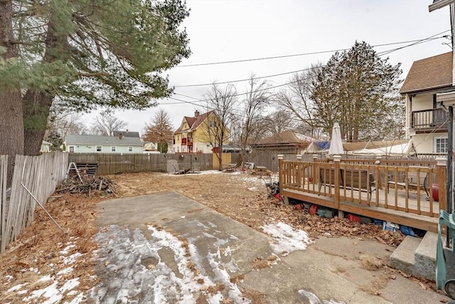 snowy yard featuring a wooden deck and a patio