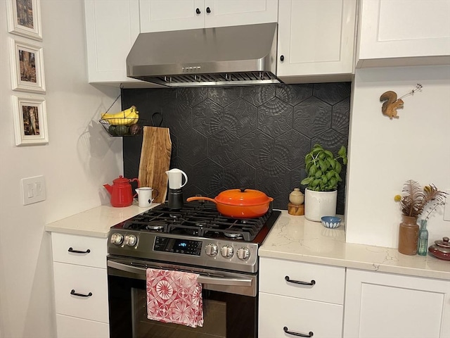 75 Rossmore Rd Unit 5, Boston, MA 02130 - kitchen featuring stainless steel gas range, wall chimney range hood, backsplash, white cabinets, and light stone counters