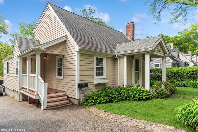 591 Poplar St, Boston, MA 02131 - view of front of house with roof with shingles, a chimney, and a front yard