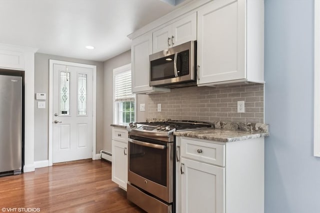 591 Poplar St, Boston, MA 02131 - kitchen featuring appliances with stainless steel finishes, a baseboard radiator, decorative backsplash, wood finished floors, and white cabinets