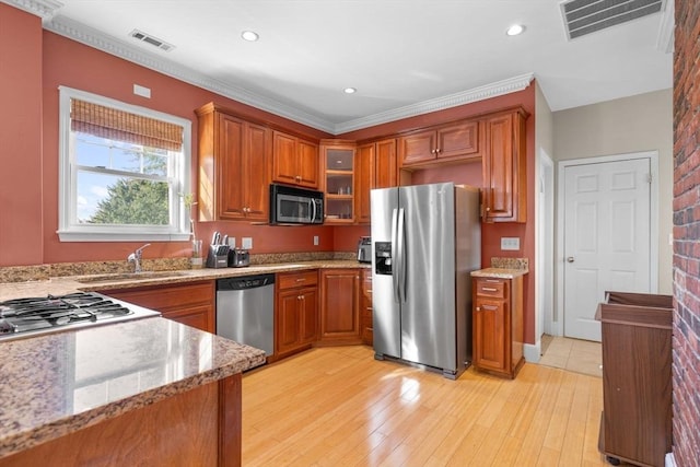 41 Standish St Unit 3, Boston, MA 02124 - kitchen with appliances with stainless steel finishes, brown cabinets, a sink, glass insert cabinets, and light stone countertops