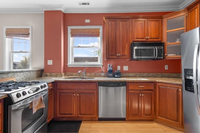 41 Standish St Unit 3, Boston, MA 02124 - kitchen featuring appliances with stainless steel finishes, a sink, light stone countertops, brown cabinets, and light wood finished floors