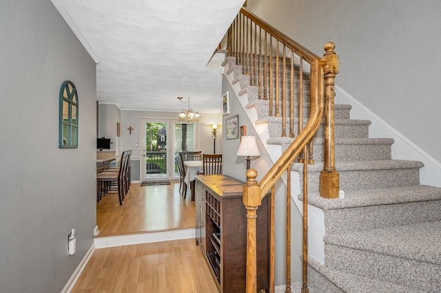 718 Wellman Ave Unit 718, Chelmsford, MA 01863 - stairs featuring wood finished floors, a chandelier, baseboards, and crown molding