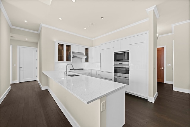 kitchen featuring tasteful backsplash, wall chimney range hood, black microwave, dark hardwood / wood-style floors, and white cabinets