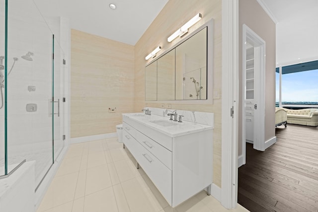 bathroom with tile floors, a shower with door, ornamental molding, and double vanity