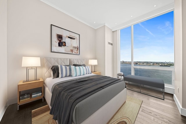 bedroom with a water view, light hardwood / wood-style floors, and multiple windows