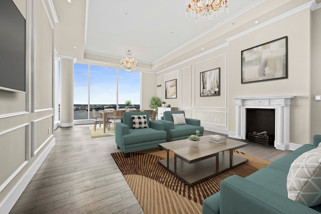 living room featuring light hardwood / wood-style flooring, a chandelier, a tray ceiling, and expansive windows