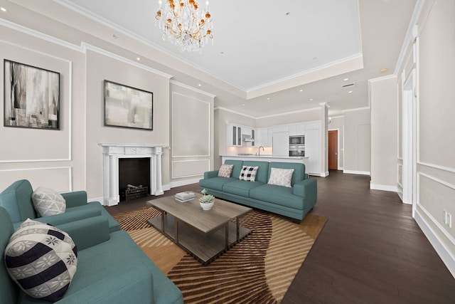 living room with a raised ceiling, sink, a chandelier, crown molding, and dark hardwood / wood-style floors