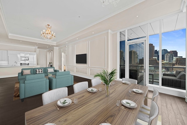 dining area featuring an inviting chandelier, sink, a tray ceiling, and wood-type flooring