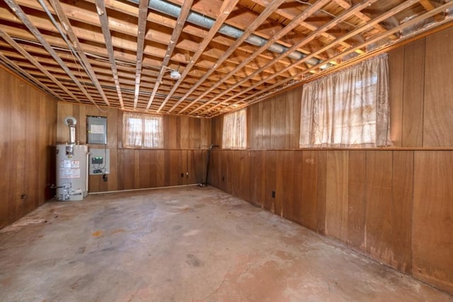 misc room featuring wood walls, concrete floors, and gas water heater