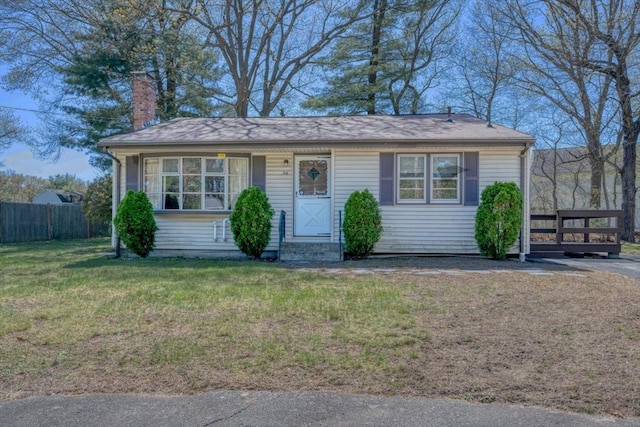 view of front of house featuring fence, a front yard, and a chimney