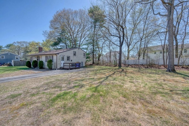 view of yard featuring a deck, fence, and driveway