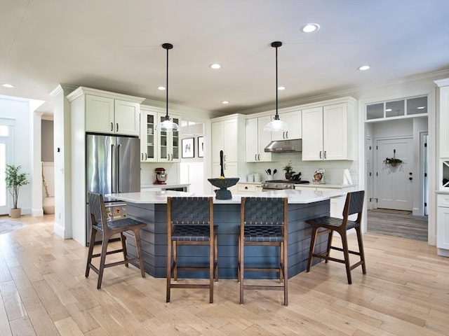 50 Bentley Ln, Westport, MA 02790 - kitchen featuring backsplash, under cabinet range hood, glass insert cabinets, light countertops, and light wood-type flooring