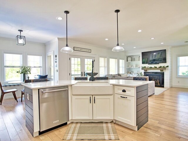 50 Bentley Ln, Westport, MA 02790 - kitchen with stainless steel dishwasher, a sink, open floor plan, a glass covered fireplace, and light countertops