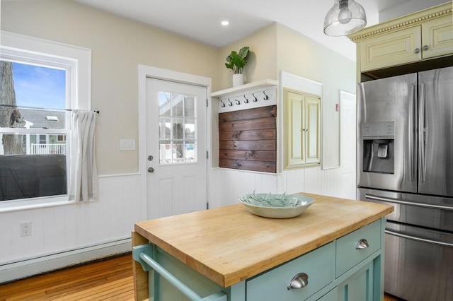 kitchen featuring a wainscoted wall, wood counters, baseboard heating, stainless steel fridge with ice dispenser, and green cabinetry