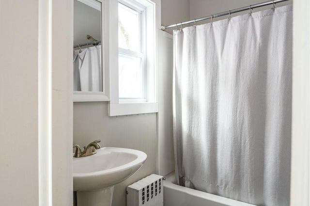 full bathroom featuring radiator heating unit, a sink, shower / bath combo with shower curtain, and a healthy amount of sunlight